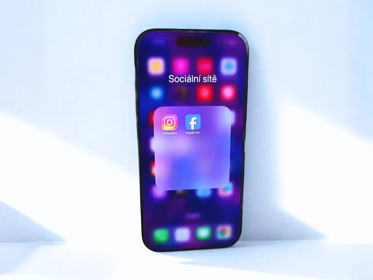 Mobilní telefon s otevřenou složkou Sociální sítě – ikony Instagramu a Facebooku v moderním neonovém stylu.